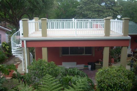Elevated sun deck on back of house with spiral stairway to walkable rooftop with vinyl railings